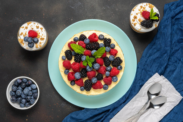 Homemade cake with fresh berries and sweet desserts on dark background.  - Photo, image