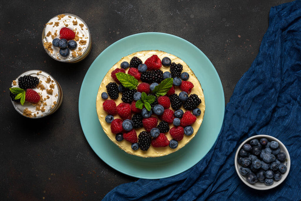 Homemade cake with fresh berries and sweet desserts on dark background.  - Foto, immagini