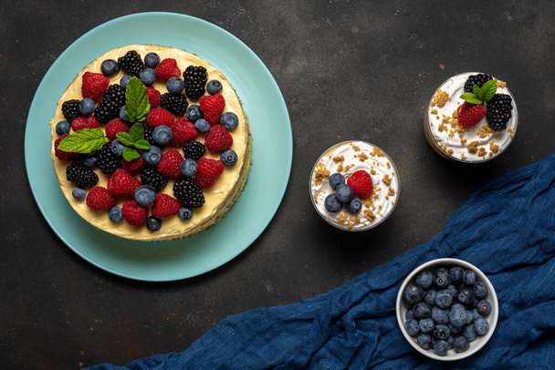 Homemade cake with fresh berries and sweet desserts on dark background.  - Zdjęcie, obraz