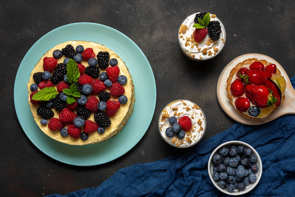 Homemade cake with fresh berries and sweet desserts on dark background.  - Foto, Imagen