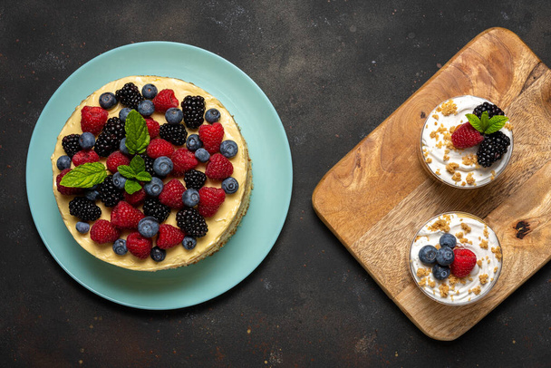 Homemade cake with fresh berries and sweet desserts on dark background.  - 写真・画像