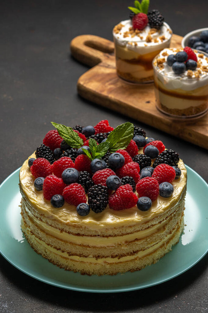 Homemade cake with fresh berries and sweet desserts on dark background.  - Foto, immagini