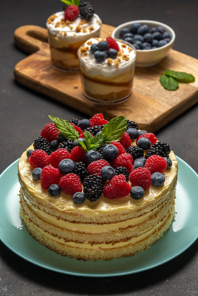 Homemade cake with fresh berries and sweet desserts on dark background.  - Photo, image
