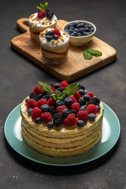 Homemade cake with fresh berries and sweet desserts on dark background.  - Foto, Imagen