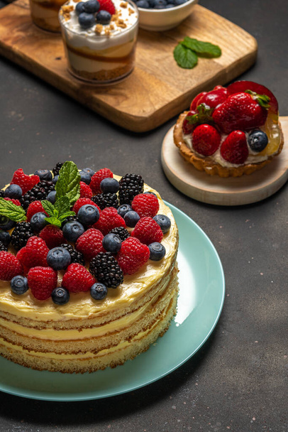 Homemade cake with fresh berries and sweet desserts on dark background.  - Fotoğraf, Görsel
