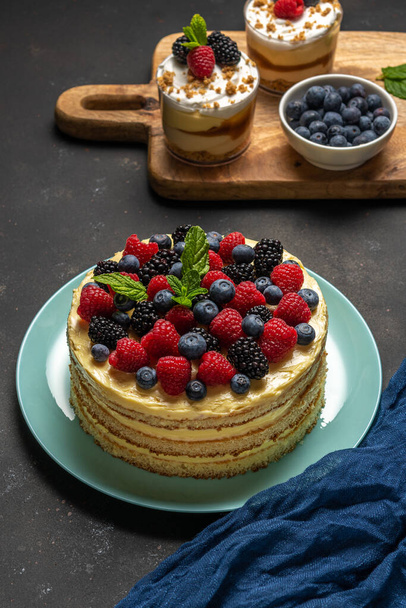 Homemade cake with fresh berries and sweet desserts on dark background.  - 写真・画像