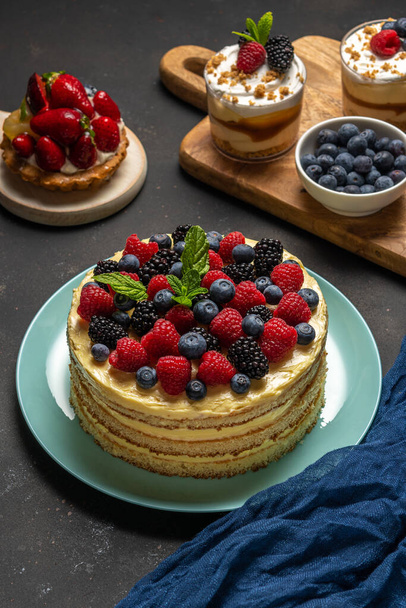 Homemade cake with fresh berries and sweet desserts on dark background.  - Photo, Image