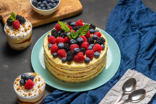 Homemade cake with fresh berries and sweet desserts on dark background.  - Foto, Bild