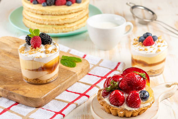 Sweet desserts with fresh berries on wooden background. - Foto, Bild