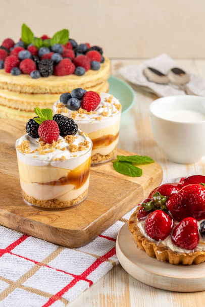 Sweet desserts with fresh berries on wooden background. - Foto, Imagen