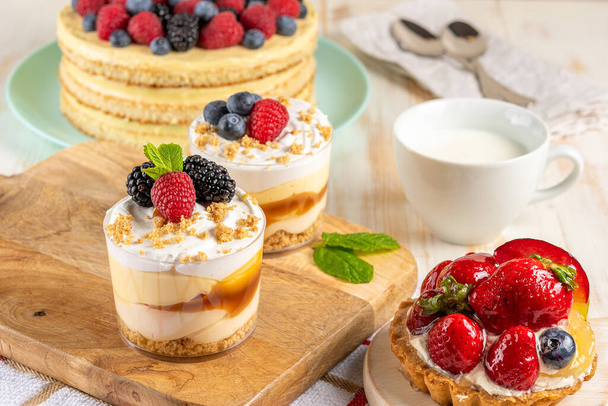 Sweet desserts with fresh berries on wooden background. - Foto, Imagen