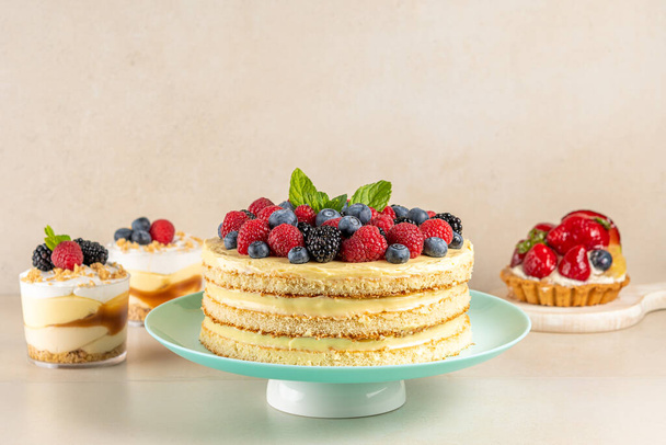 Homemade cake with fresh berries and sweet desserts on table. - 写真・画像