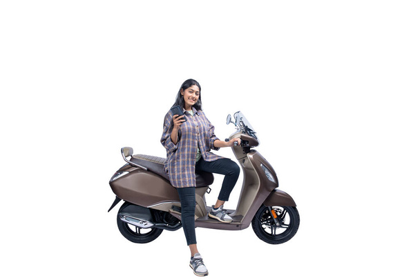 Asian woman sitting on a scooter while using a mobile phone isolated over white background - Fotoğraf, Görsel