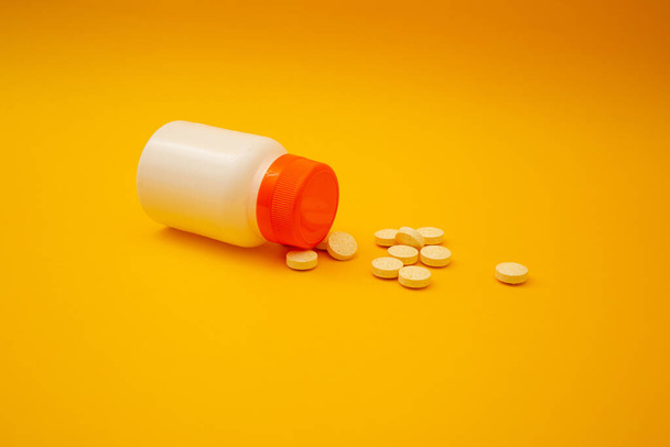 Potje met pillen op een gele achtergrond - Foto, afbeelding