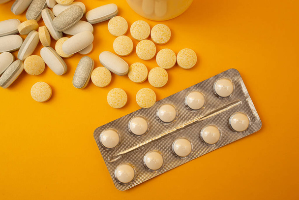 White pills on a yellow background, medical theme - Foto, afbeelding