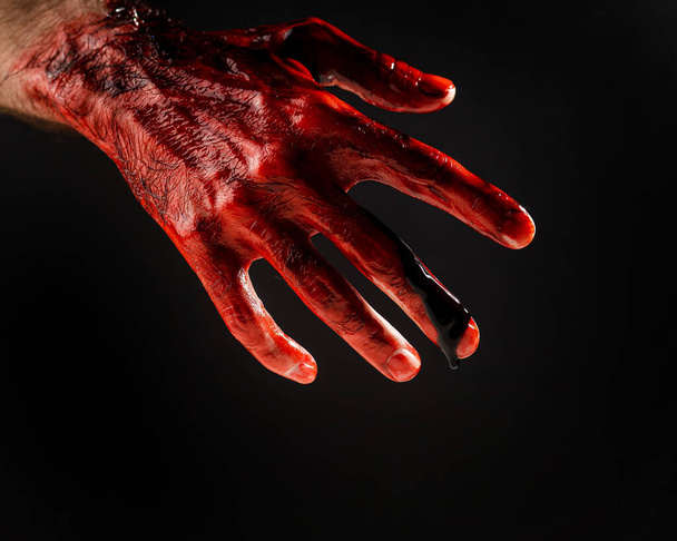 Close-up of a male hand stained with blood on a black background - Photo, image