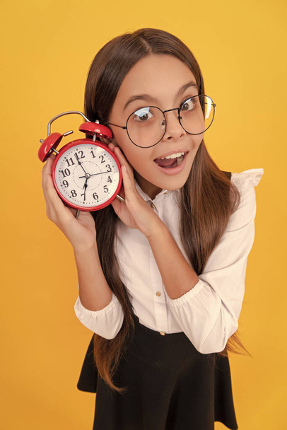 amazed child in school uniform and glasses listen alarm clock ringing showing time, amazement. - Valokuva, kuva