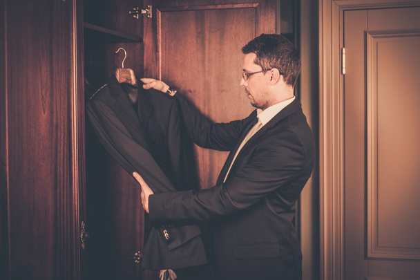 Középkorú férfi, figyelembe véve a ruha szekrény  - Fotó, kép