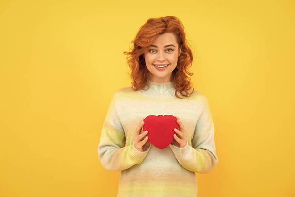 happy redhead woman with red heart on yellow background. love. - Foto, Imagen