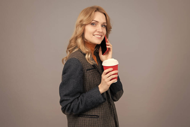 強化されたライフスタイルのためのコーヒー。幸せな女性は携帯電話で使い捨てカップを保持します。現代の生活。コーヒー休憩。お茶の時間。インスピレーションを飲む. - 写真・画像