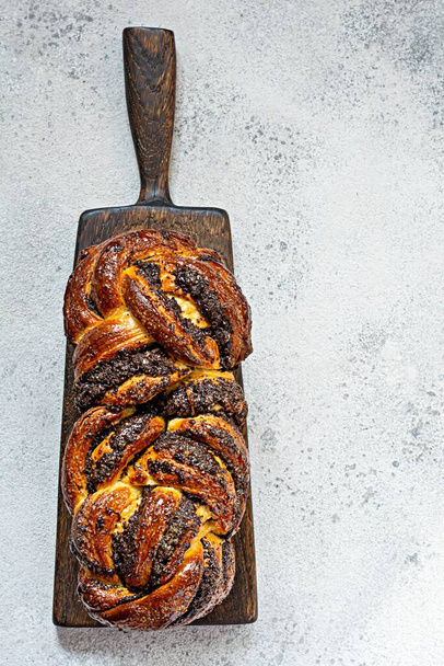 Freshly baked brioche/Babka with poppy seeds and chocolate on a wooden board. Braided dessert bread. Homemade baking, national pastries. Estonian kringle in the shape of a brick. - Foto, afbeelding