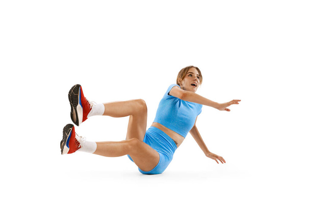 Landing. Triple jump technique. Young professional female athlete in sports uniform jumping isolated on white background. Concept of sport, action, motion, speed, healthy lifestyle. Copy space for ad - Foto, afbeelding