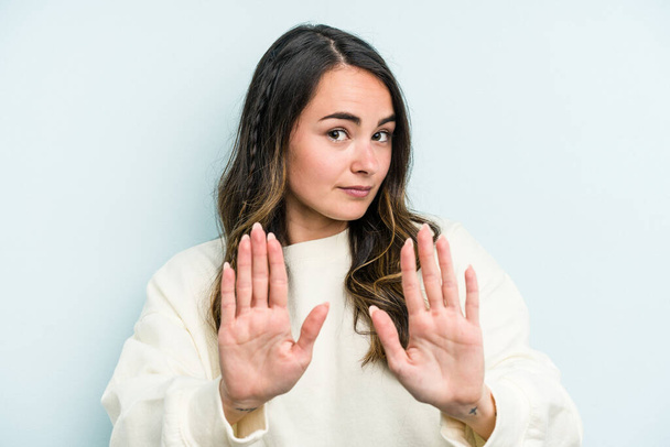 Jonge blanke vrouw geïsoleerd op blauwe achtergrond staan met uitgestrekte hand tonen stop teken, voorkomen dat u. - Foto, afbeelding