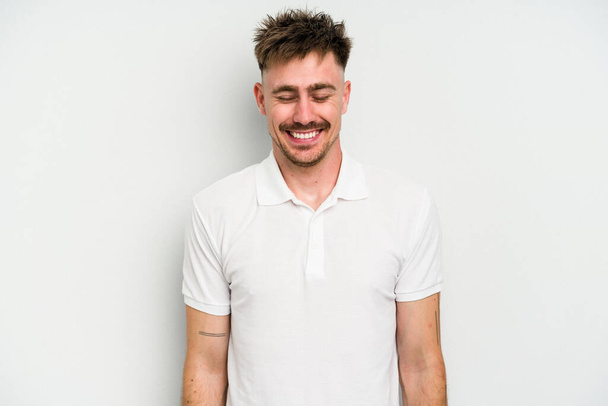 Young caucasian man isolated on white background laughs and closes eyes, feels relaxed and happy. - Photo, Image