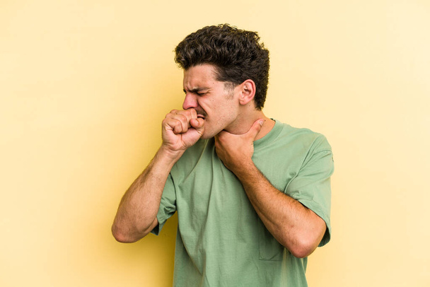 Young caucasian man isolated on yellow background suffers pain in throat due a virus or infection. - Foto, imagen
