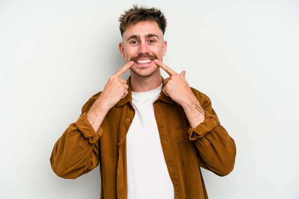 Young caucasian man isolated on white background smiles, pointing fingers at mouth. - Photo, Image