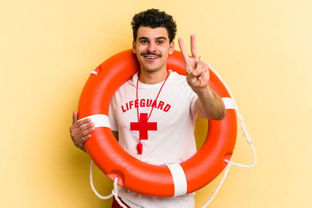 Young caucasian lifeguard man isolated on yellow background showing number two with fingers. - Foto, immagini