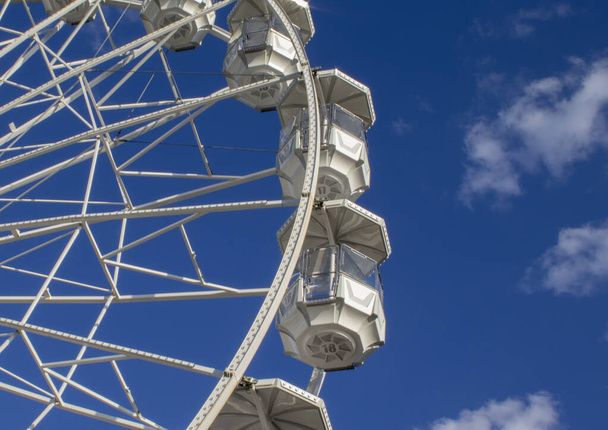 Ferris wheel in an amusement park in Italy. A giant wheel against the blue summer sky during the day, the festival begins in the evening when it gets dark. - Zdjęcie, obraz