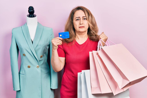 Middle age caucasian woman holding shopping bags and credit card depressed and worry for distress, crying angry and afraid. sad expression.  - Foto, afbeelding