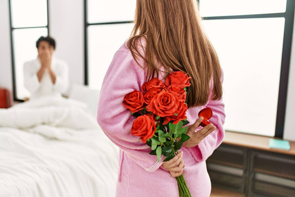 Žena překvapující její přítel s kyticí růží v ložnici. - Fotografie, Obrázek