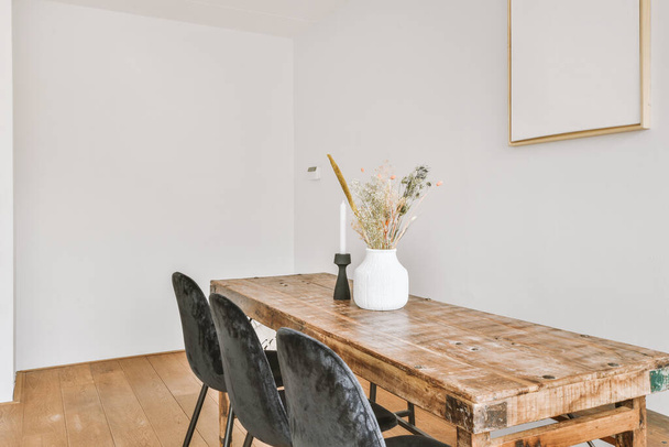 Mukavat tuolit tyynyt ja sohva sijaitsevat lähellä pöytää valaisimien alla tyylikkäässä ruokasalissa nykyaikaisessa huoneistossa - Valokuva, kuva
