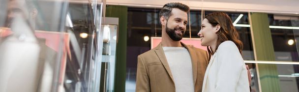 Низкий угол зрения улыбающегося клиента, обнимающего подругу в ювелирном магазине, баннер  - Фото, изображение
