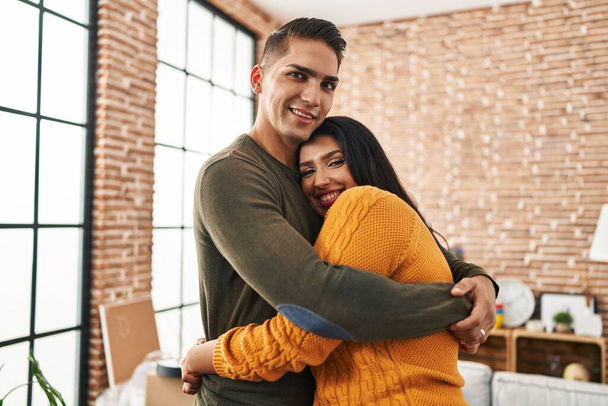 man en vrouw paar knuffelen elkaar staan in nieuw huis - Foto, afbeelding