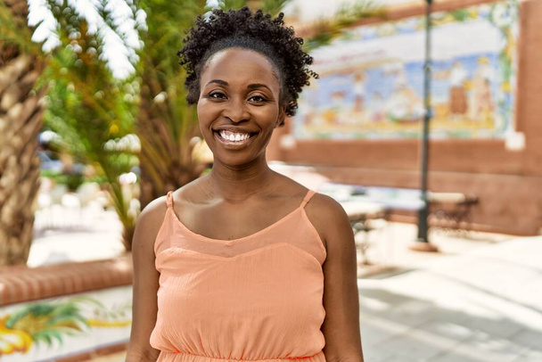 Νεαρή Αφροαμερικανή γυναίκα χαμογελά ευτυχισμένη μια καλοκαιρινή μέρα - Φωτογραφία, εικόνα