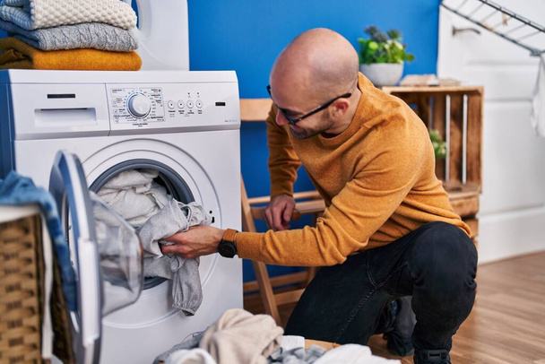 Mladý muž usměvavý sebevědomé praní oblečení v prádelně - Fotografie, Obrázek