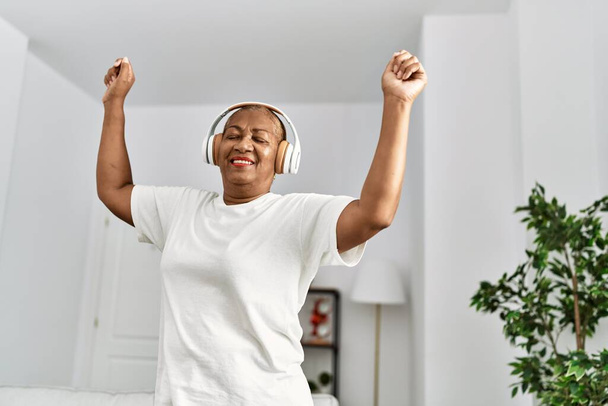 Mujer afroamericana mayor sonriendo confiada y bailando en casa - Foto, imagen
