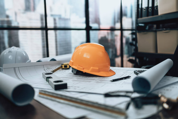 Engineer safety helmet with drawings inspection on the office desk and Calculator, triangle ruler, safety glasses, compass, vernier caliper on Blueprint. Engineer, Architect, Industry and factory concept. - Foto, immagini
