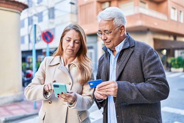 Homem e mulher de meia idade casal usando smartphone e cartão de crédito na rua - Foto, Imagem