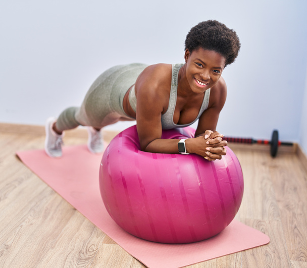 afro-américaine femme souriant entraînement confiant abs exercice au centre sportif - Photo, image