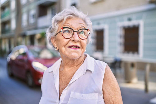 Ältere grauhaarige Frau lächelt zuversichtlich, wenn sie auf der Straße steht - Foto, Bild