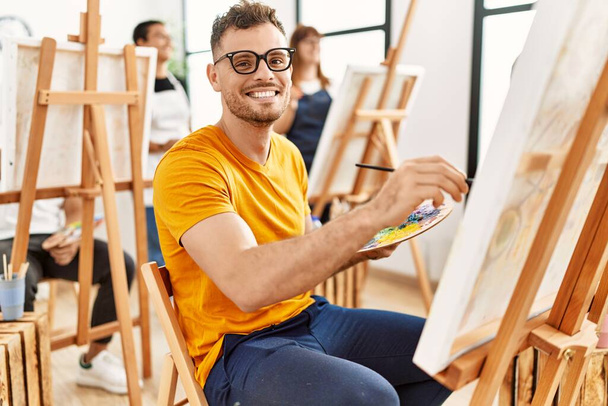 Молодий чоловік усміхається щасливий малюнок з групою людей в художній студії
. - Фото, зображення