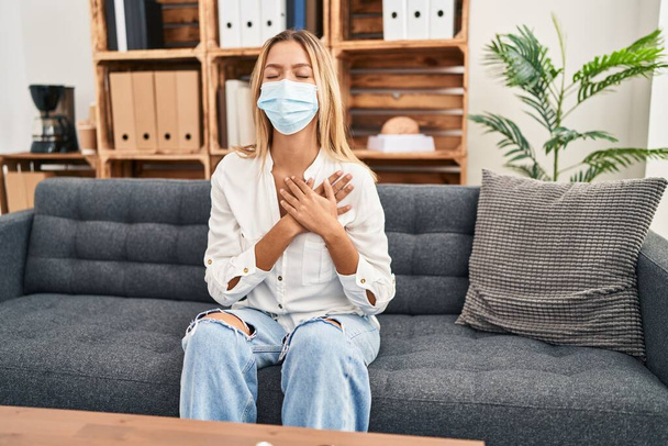 Young blonde woman treating covid fear at therapy smiling with hands on chest, eyes closed with grateful gesture on face. health concept.  - Foto, imagen