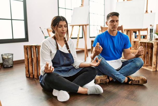 Dois estudantes de pintura se concentraram sentados no chão fazendo pose de ioga na escola de arte. - Foto, Imagem