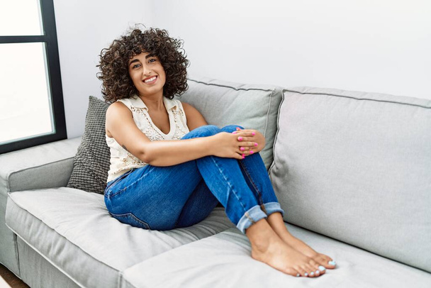 Joven mujer de Oriente Medio sonriendo confiado sentado en el sofá en casa - Foto, Imagen