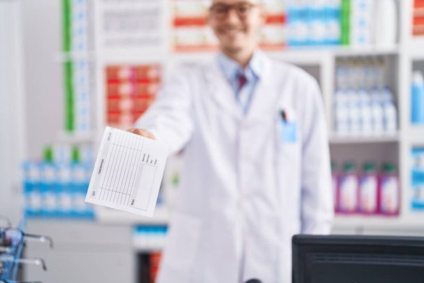 Молодий кавказький чоловік фармацевт тримає рецепт в аптеці
 - Фото, зображення