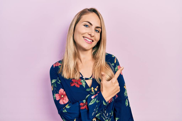 Young caucasian woman wearing casual clothes cheerful with a smile of face pointing with hand and finger up to the side with happy and natural expression on face  - Photo, Image
